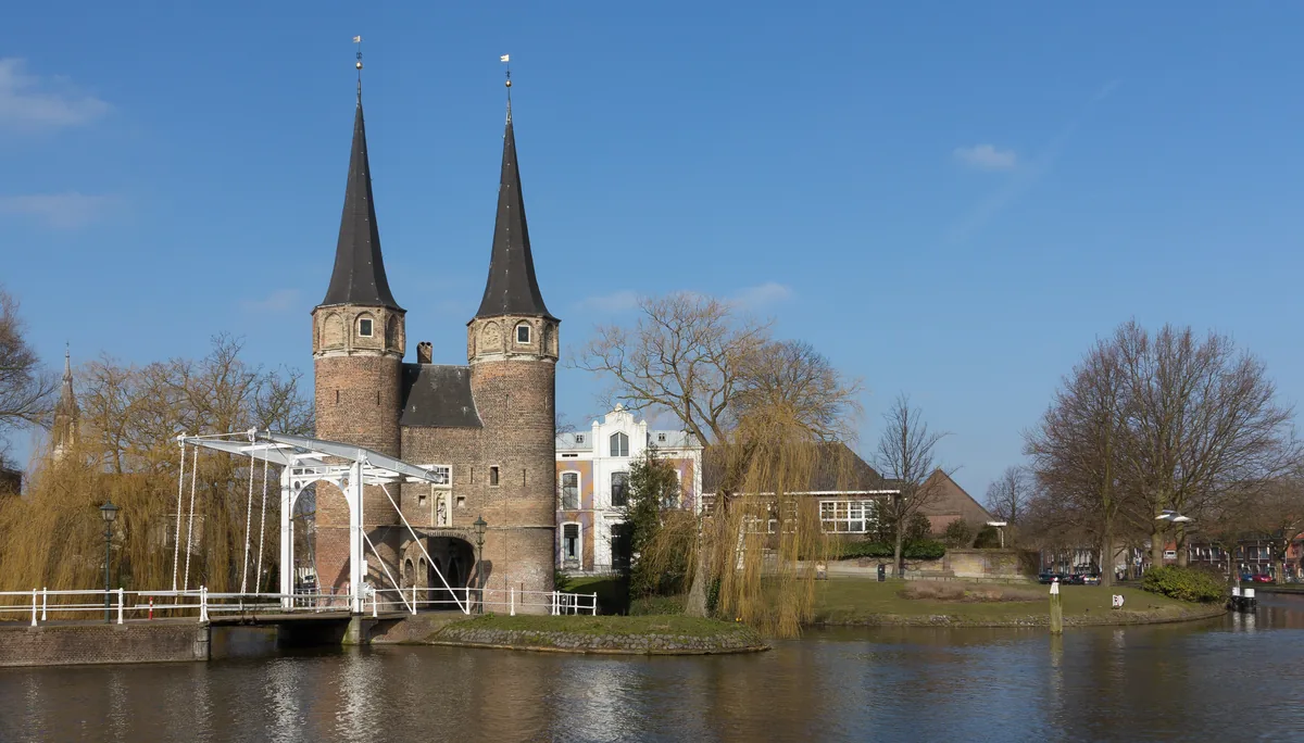De historische Oostpoort van Delft met ophaalbrug en weerspiegeling in het water.