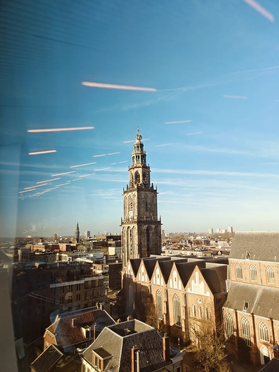 Martinitoren en Martinikerk gezien door een raam van Forum Groningen.