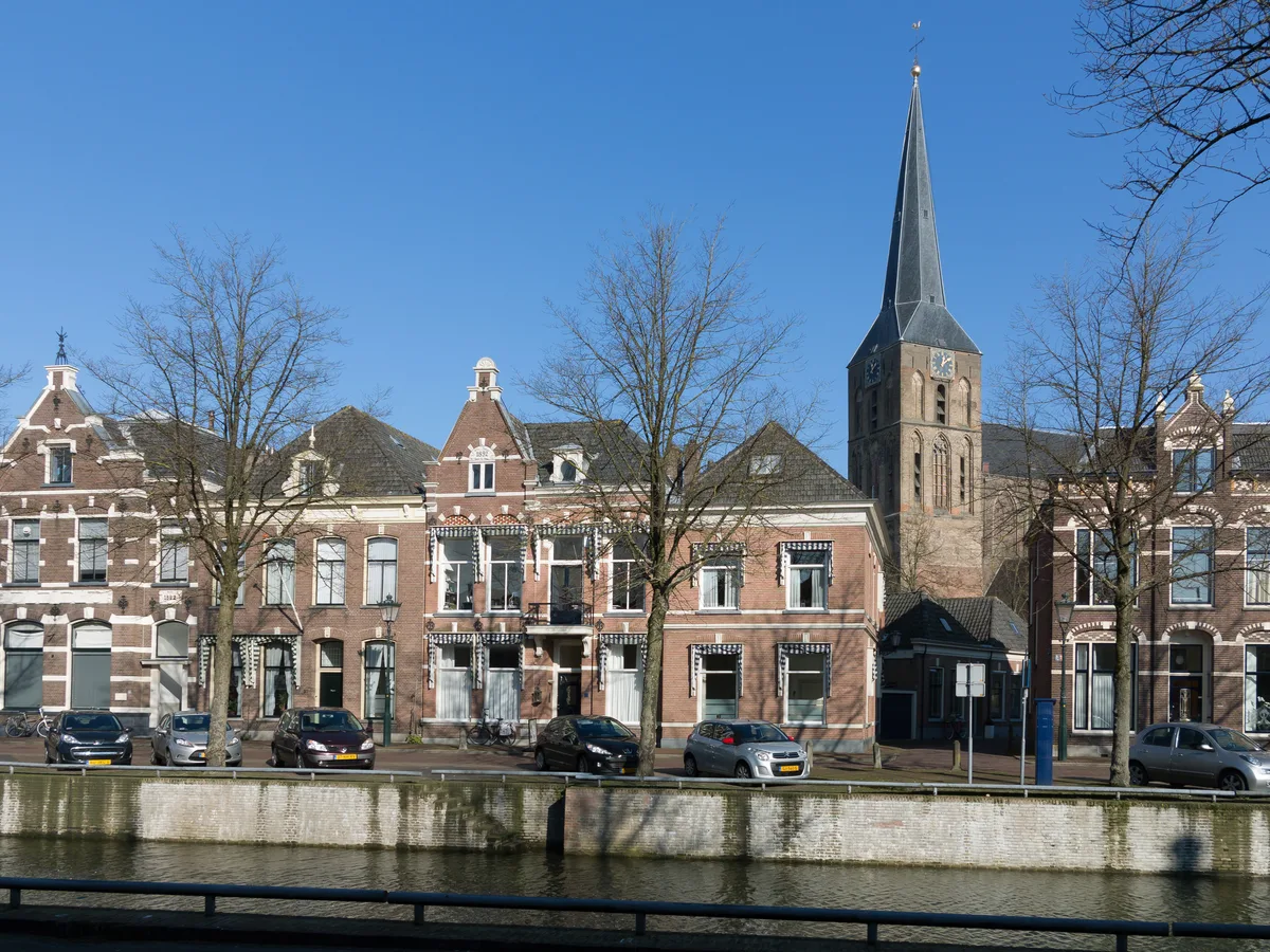 Bovenkerktoren boven historische gevels en een gracht in Kampen