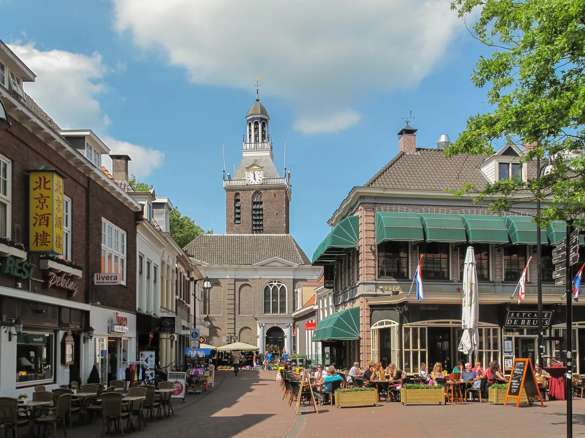 Meppeler Toren boven een historische straat met terrassen in Meppel