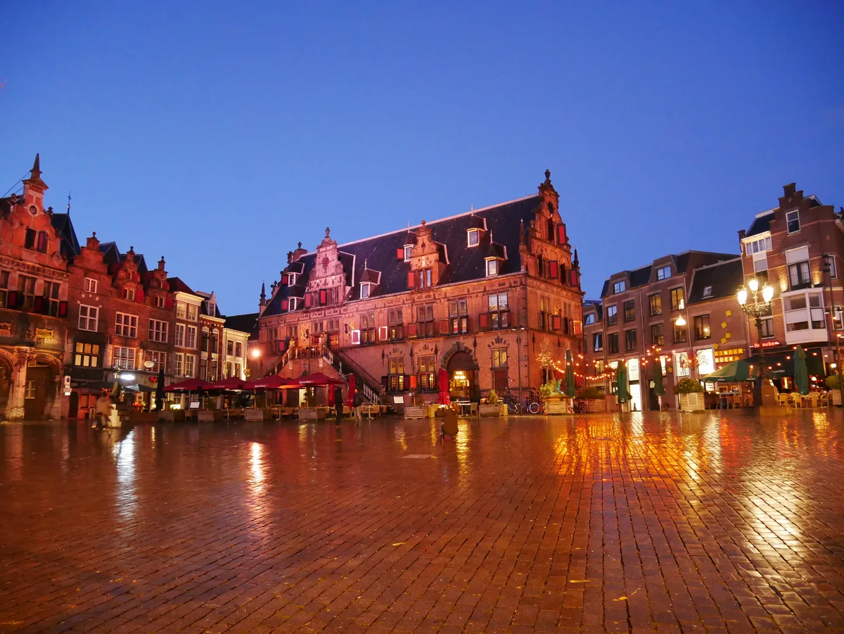 Verlichte historische gevels aan de Grote Markt in Nijmegen bij avond.