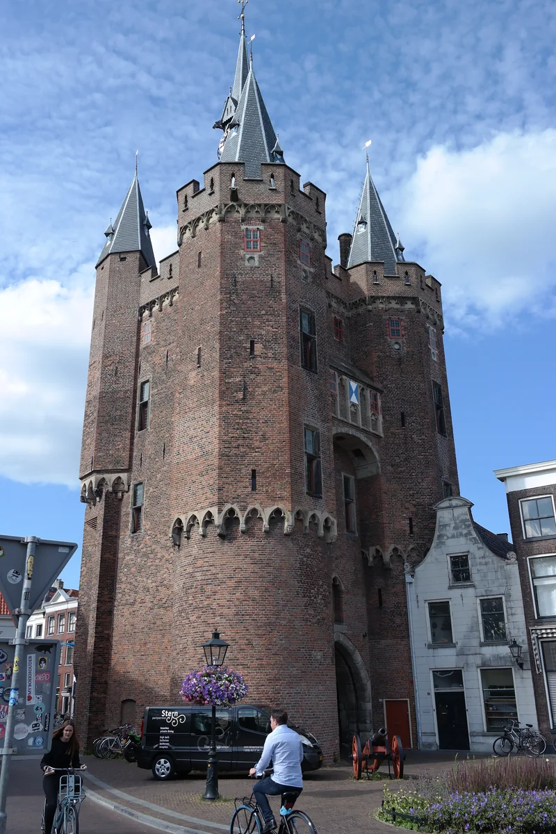 De bakstenen Sassenpoort met torens tegen een wolkenlucht in Zwolle.